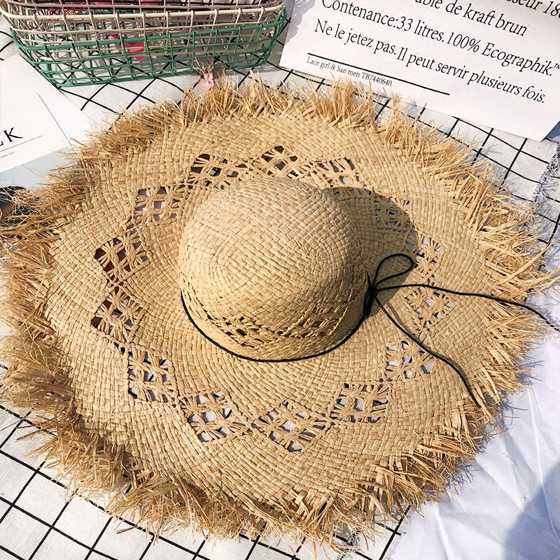 A big brim Rustic Fringe Temperament Beach Hat by Beachy Cover Ups on a table.