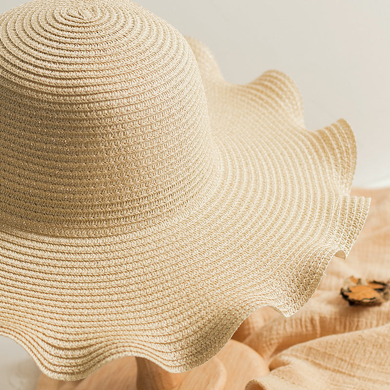 A Foldable Wavy Edge Windproof Beach Hat by Beachy Cover Ups on top of a wooden stand.