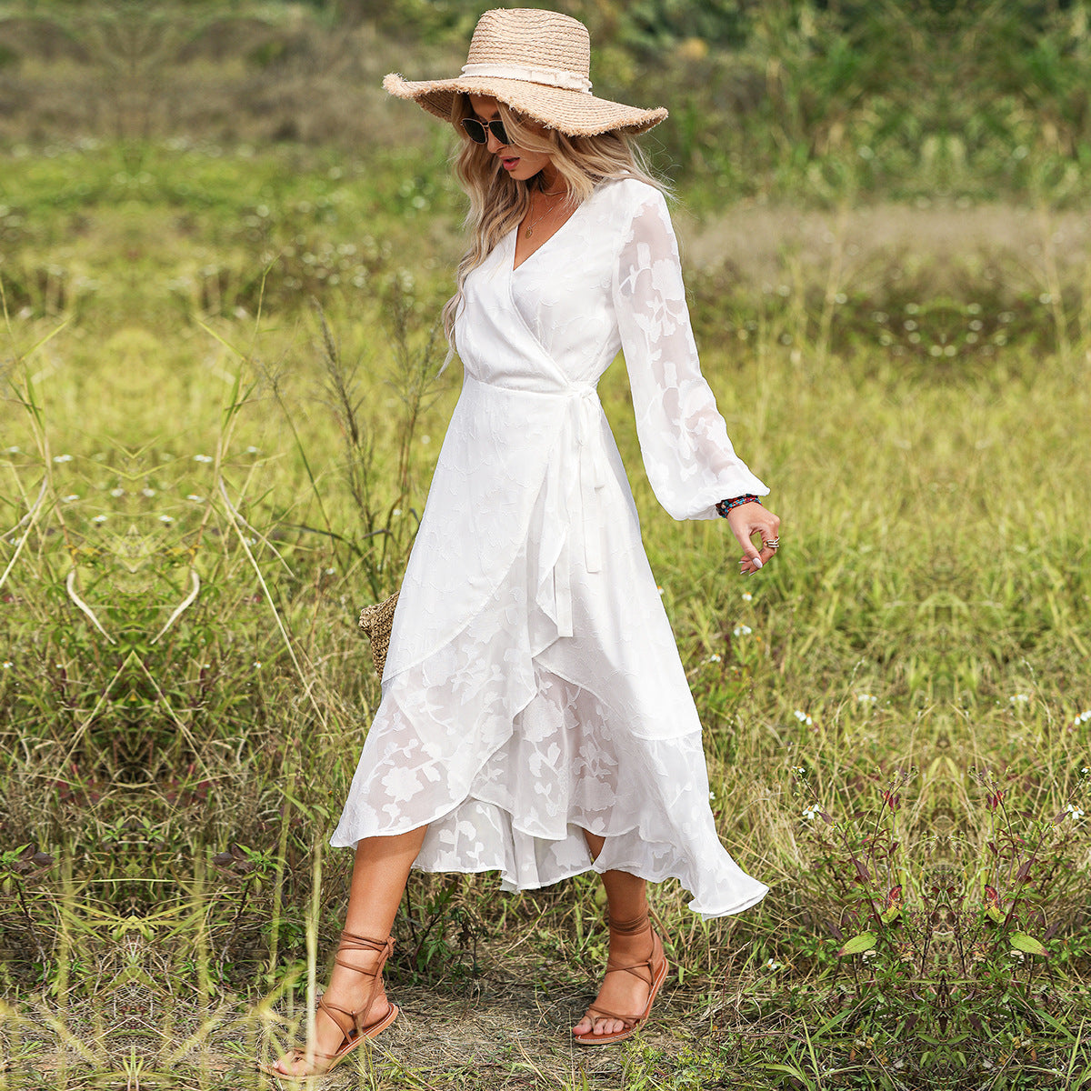 A woman in a white Beachy Cover Ups Long Sleeve V Neck Beach Dress walking through a field with a straw hat.