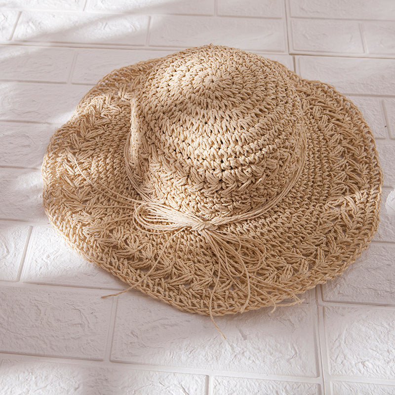 A stylish Foldable Seaside Beach Hat by Beachy Cover Ups on a white tile floor.