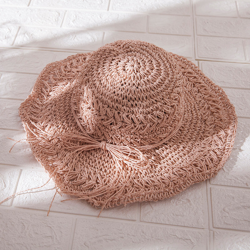 A Foldable Seaside Beach Hat by Beachy Cover Ups on a white tile floor.