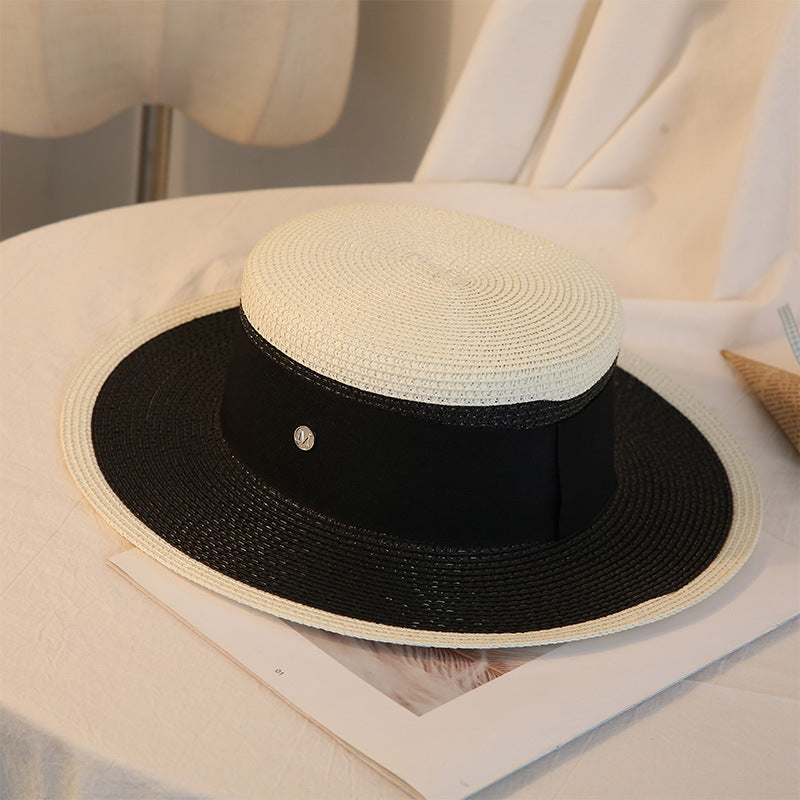 A Retro Flat Top Straw Beach Hat by Beachy Cover Ups on a table.