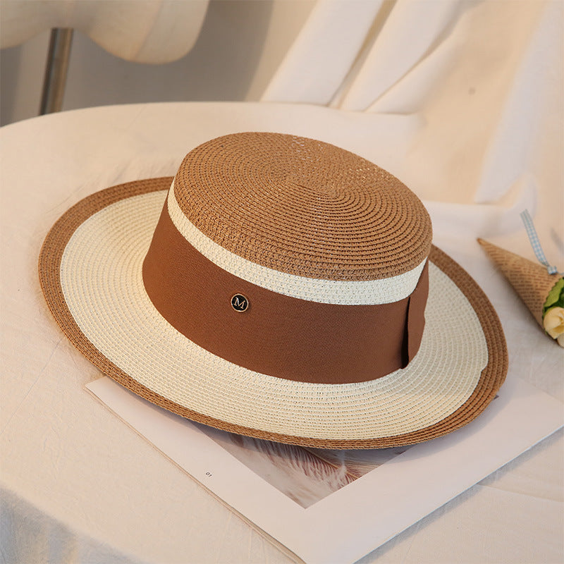 A Retro Flat Top Straw Beach Hat by Beachy Cover Ups on a table.