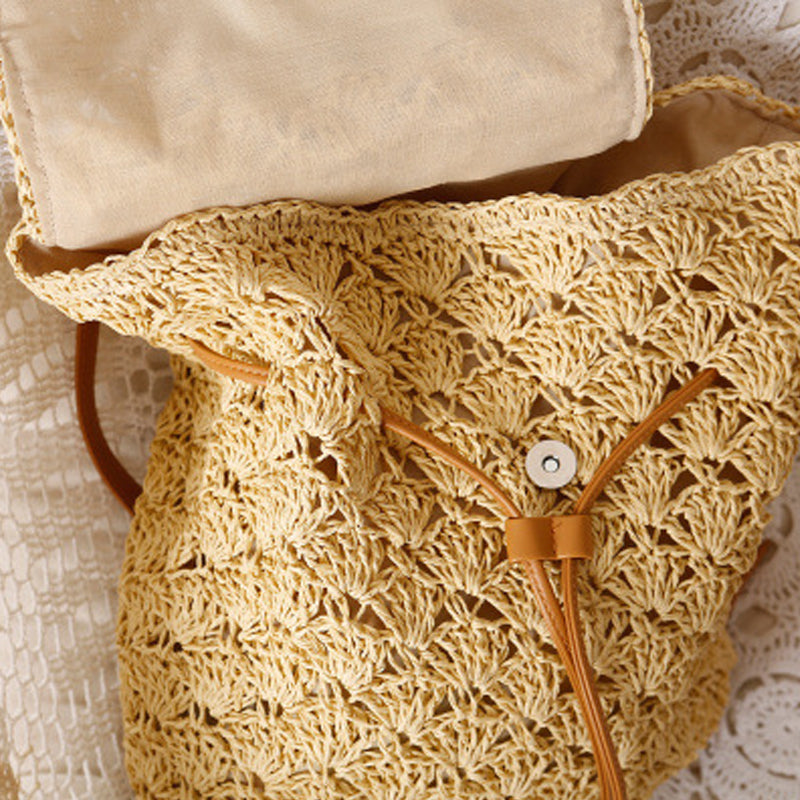 A Resort Holiday Straw Woven Beach Bag from Beachy Cover Ups is sitting on top of a lace doily.