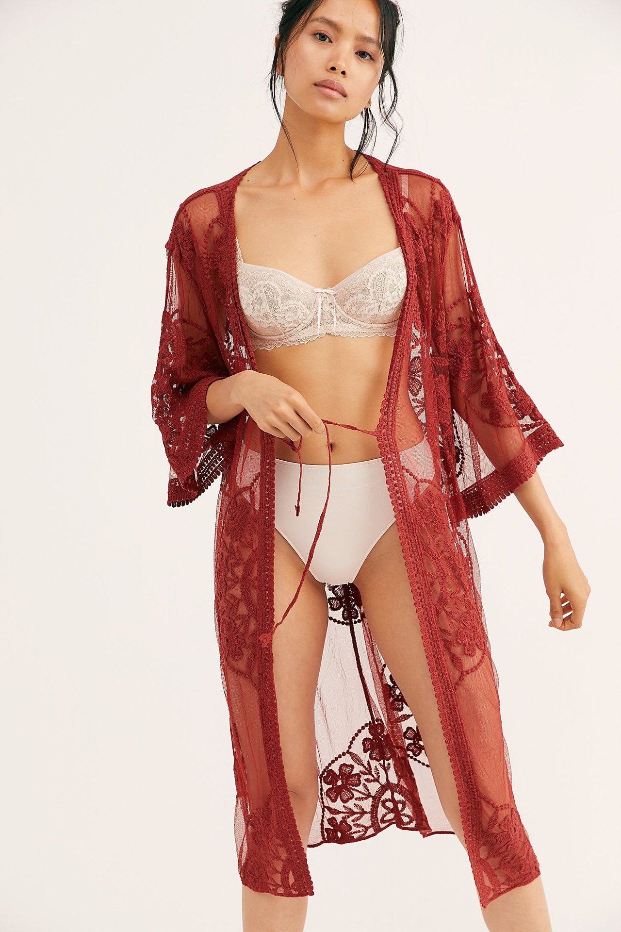 A woman wearing a red Beachy Cover Ups Lace Mesh Crochet Beach Jacket Cover Up and lingerie.