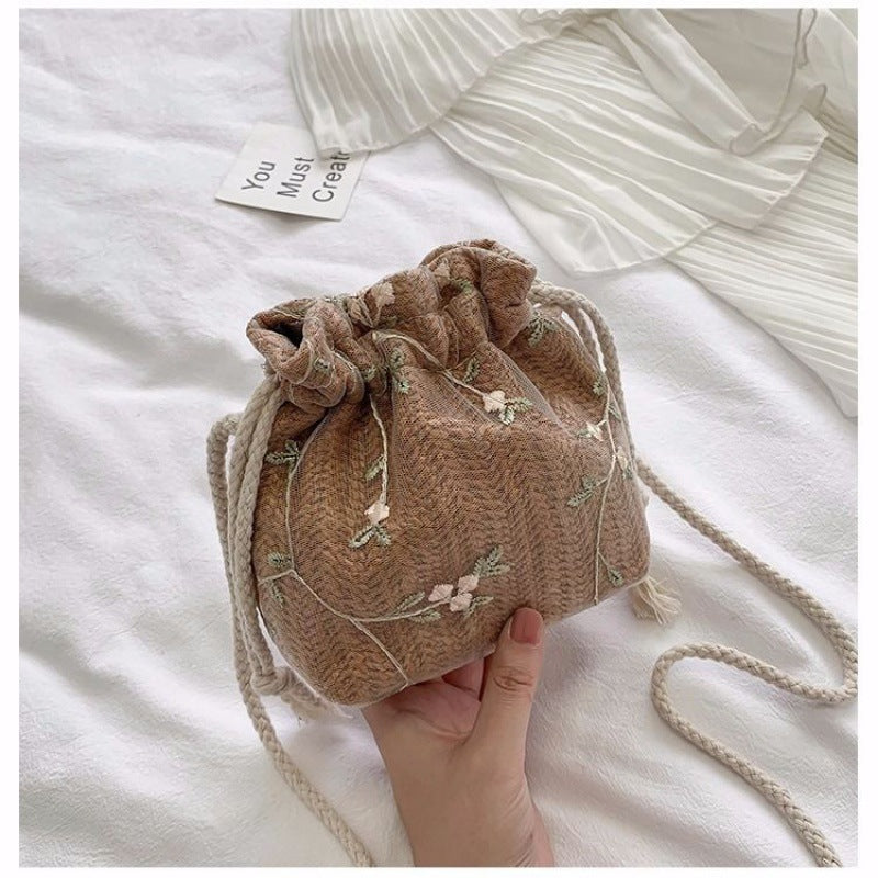 A hand holding a small brown drawstring bag with Floral Lace Vacation Beach Bag by Beachy Cover Ups.