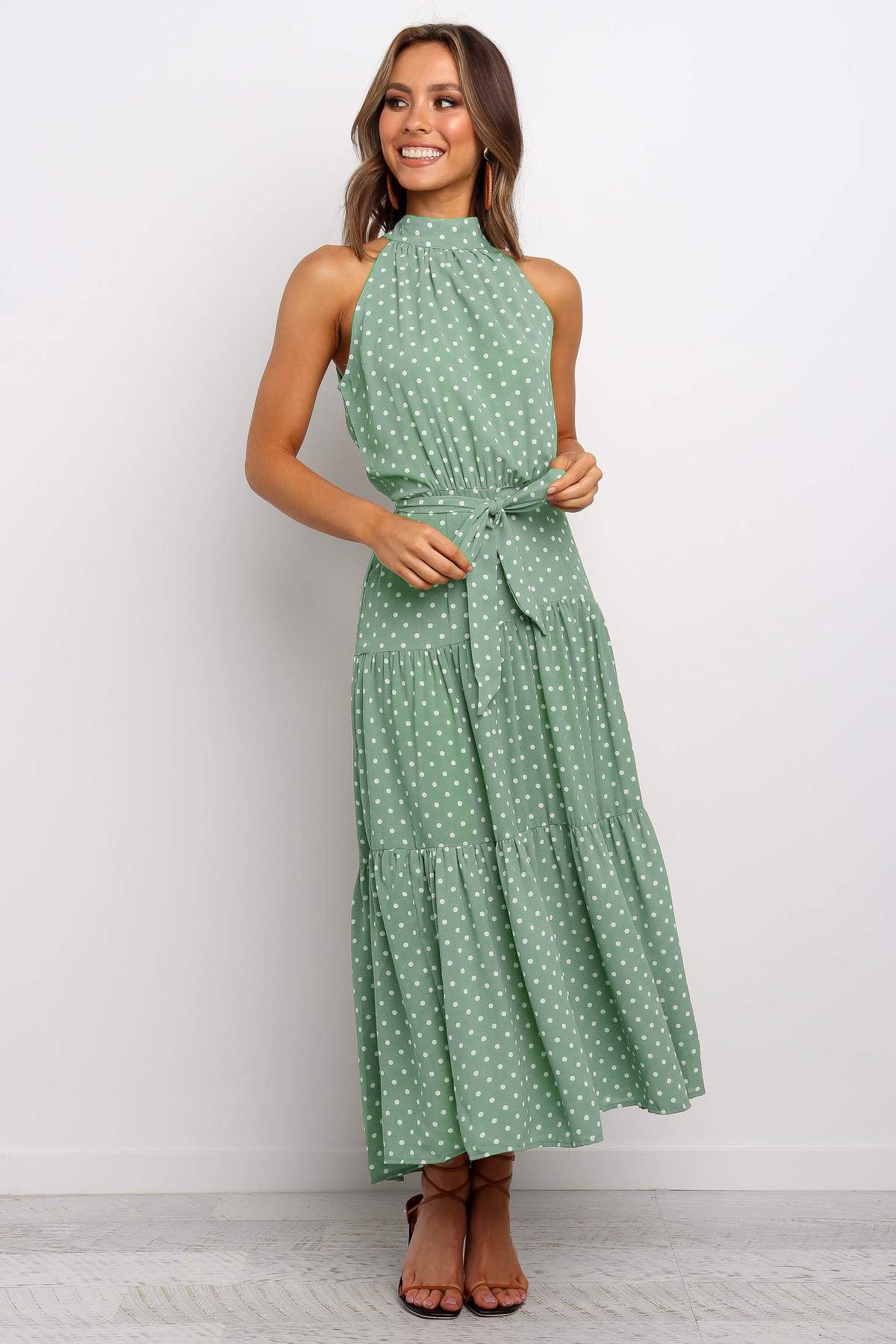 A woman wearing a Floral Or Polka Halter long Dress With Front Ribbon Tie from Beachy Cover Ups provides customer service.