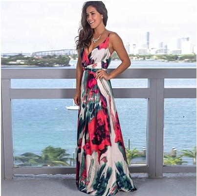 A woman is standing on a balcony wearing a Long Floral Resort Beach Dress by Beachy Cover Ups, exuding tropical elegance.