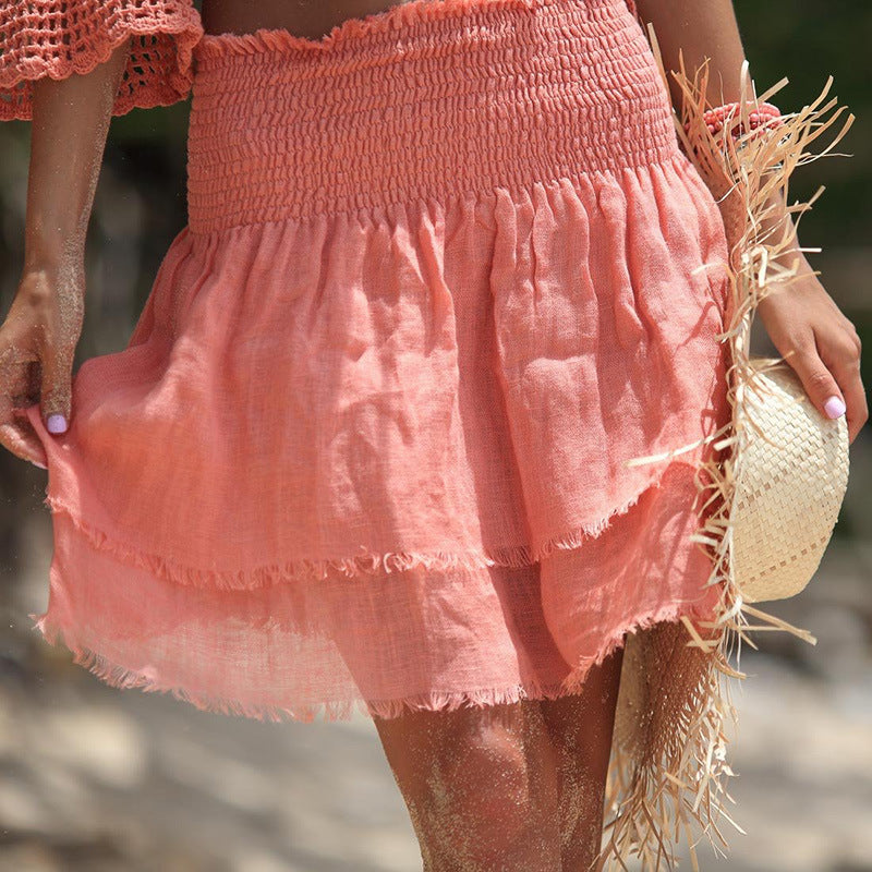 A woman wearing Fringed Summer Cotton Beach Shorts by Beachy Cover Ups and a straw hat on the beach.