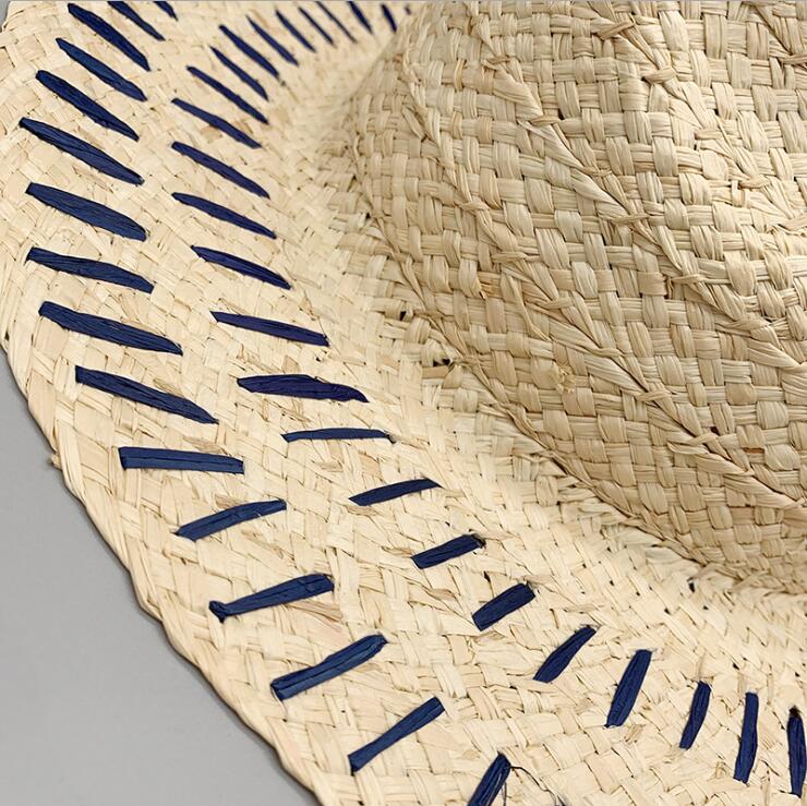 A Summer Tiny Stipes Straw Hat by Beachy Cover Ups with blue stripes on it.