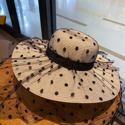 A Big Brim Lace Mesh Polka Dot Beach Hat by Beachy Cover Ups on top of a table.