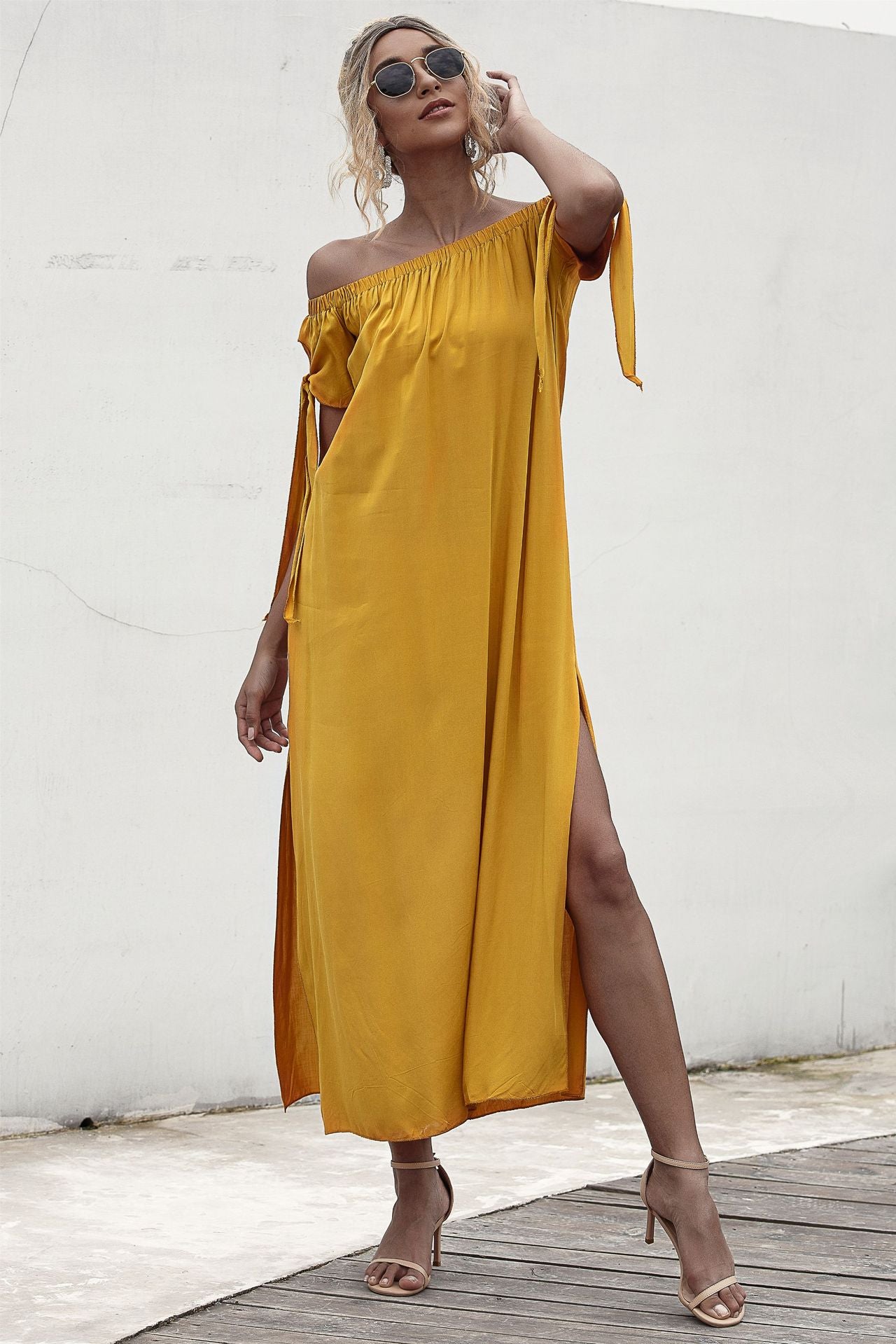 A woman is posing in a yellow Summer Straight Shoulder Split Beach Dress by Beachy Cover Ups.