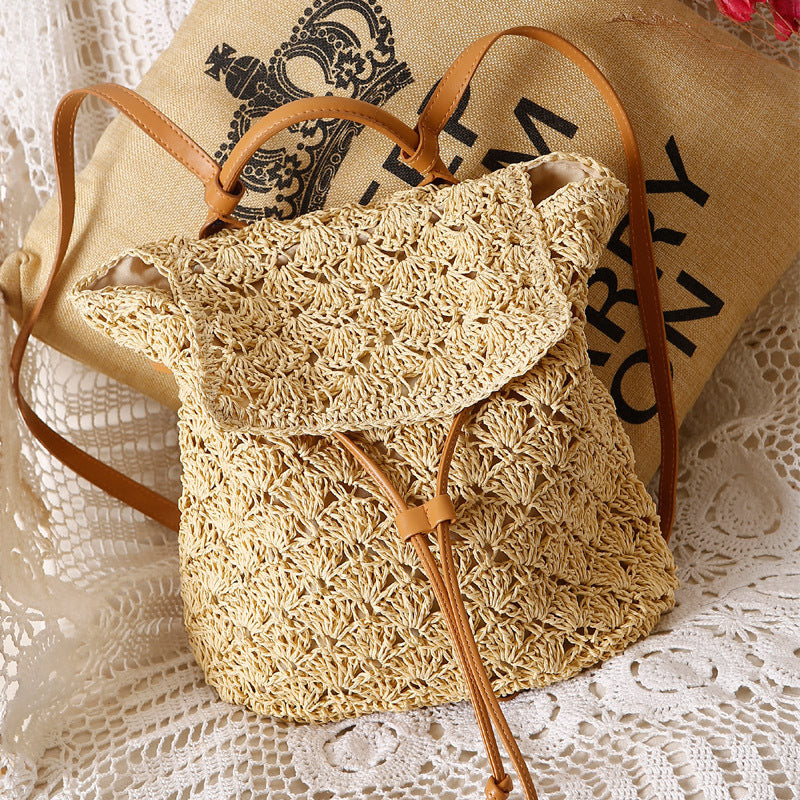 A small Resort Holiday Straw Woven Beach Bag from Beachy Cover Ups sitting on a lace table.