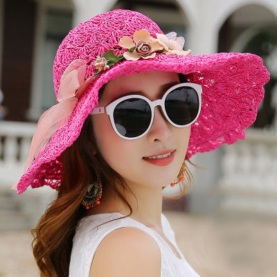 A woman wearing a Floral Foldable Big Brim Beach Straw Hat by Beachy Cover Ups and sunglasses.