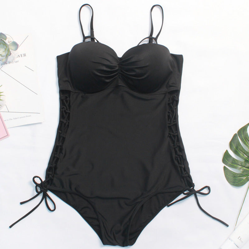 A comfortable Slimming Black Plus Size One-Piece Swimsuit Side Design by My Store on a table next to a plant.