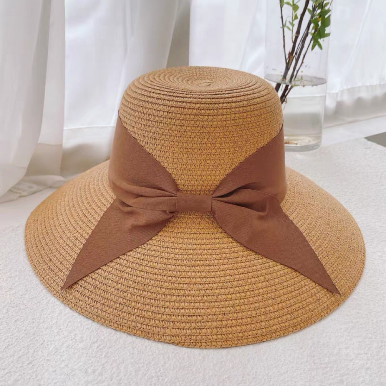 A Straw Hat Foldable Beach Sunshade with a bow on it, perfect for beach days and providing sunshade by Beachy Cover Ups.