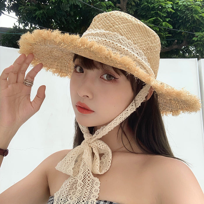 A woman wearing a Fringed Seaside Beach lace sun hat by Beachy Cover Ups with a lace bow tie.