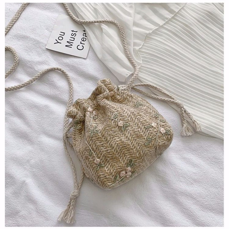 A small beige Beachy Cover Ups Floral Lace Vacation Beach Bag on a white bed.