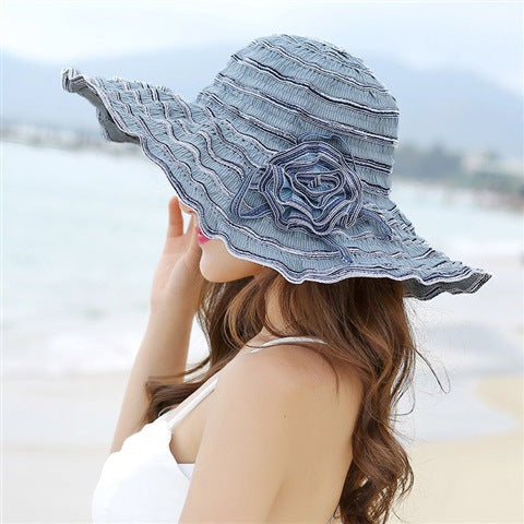 A woman wearing a Rippled Colored Flower Beach Hat by Beachy Cover Ups on the sand.