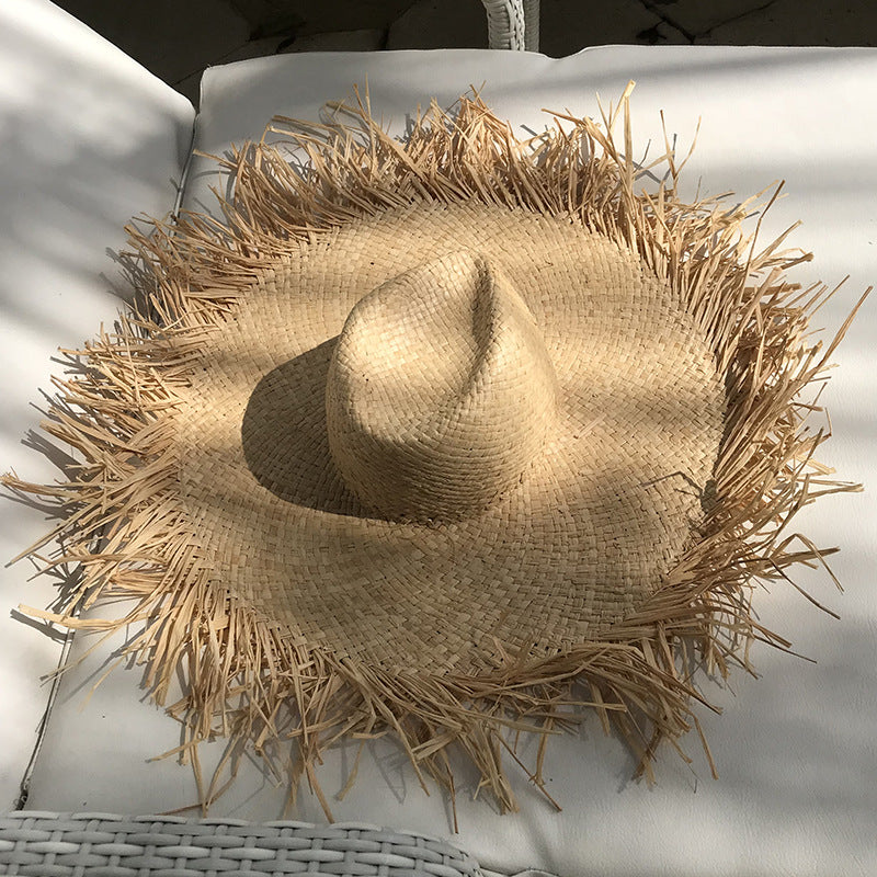 A female wearing a Rustic Fringe Temperament Beach Hat made by Beachy Cover Ups sitting on top of a white chair.