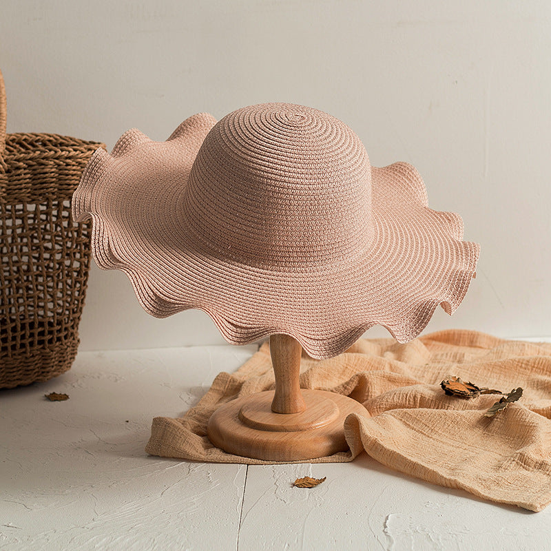 A Foldable Wavy Edge Windproof Beach Hat by Beachy Cover Ups on a table.