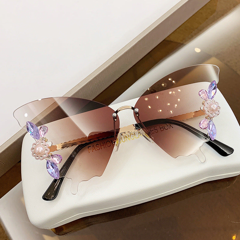 Elegant Diamond Butterfly sunglasses by Beachy Cover Ups on a table.