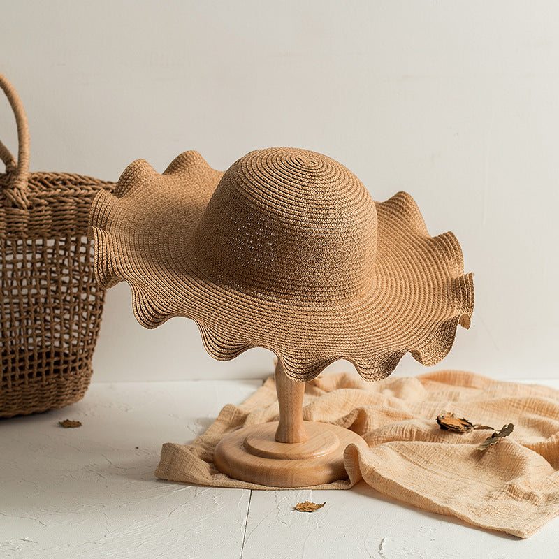 A Foldable Wavy Edge Windproof Beach Hat by Beachy Cover Ups and a windproof wicker basket on a table.