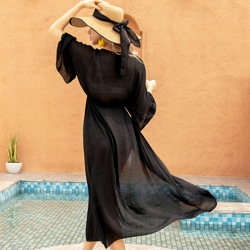 A woman in a black dress standing next to a pool, showcasing Beachy Cover Ups' Retro Style Beach Cover Up, exuding vintage seaside elegance.