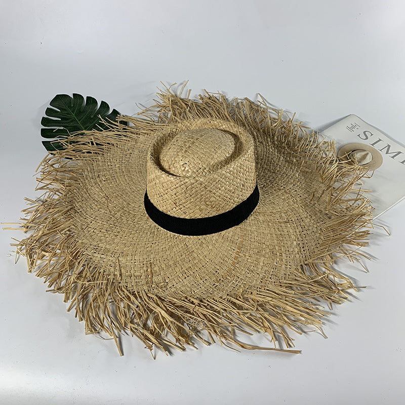 A Rustic Fringe Temperament Beach Hat with fringes and a leaf next to it. (Brand: Beachy Cover Ups)