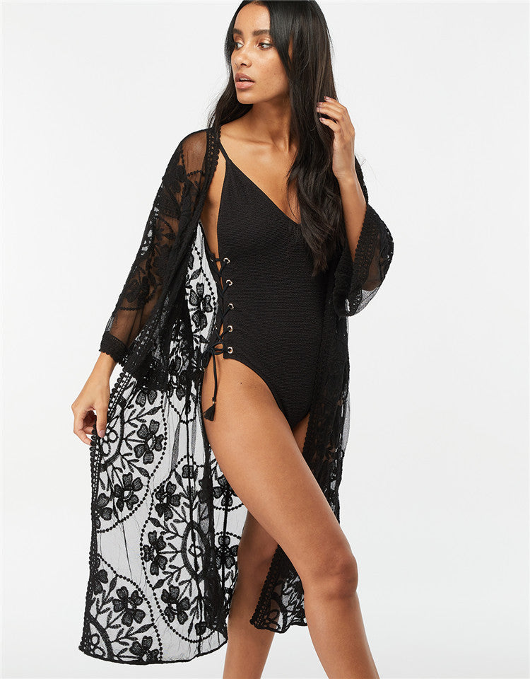 A woman wearing a Beachy Cover Ups' Lace Mesh Crochet Beach Jacket Cover Up bathing suit.