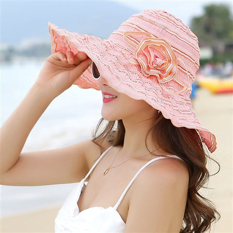 A woman wearing a Rippled Colored Flower Beach Hat by Beachy Cover Ups.